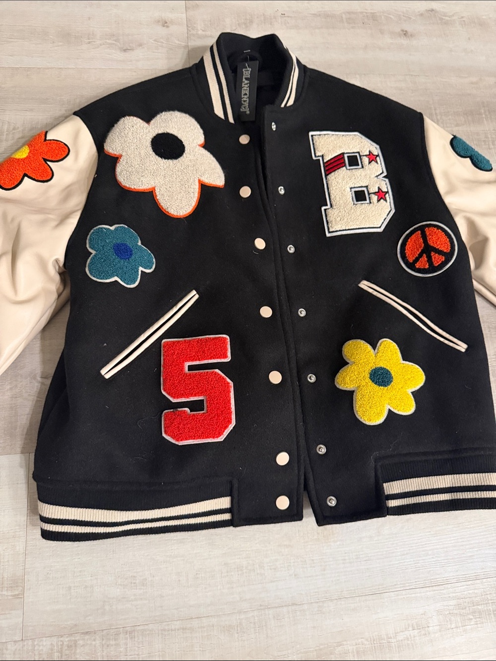 Blank NYC Black and Cream Varsity Jacket with Colorful Flower Appliqués